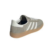 Gray Adidas sneaker with white stripes on a light gray background
