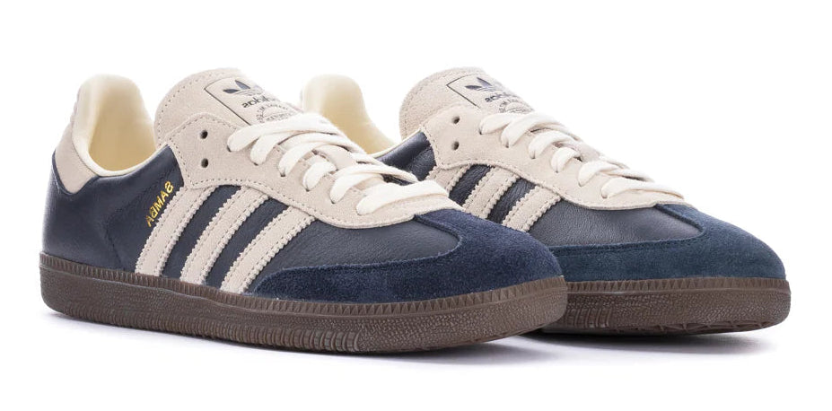 Pair of navy and white sneakers with three stripes on a white background